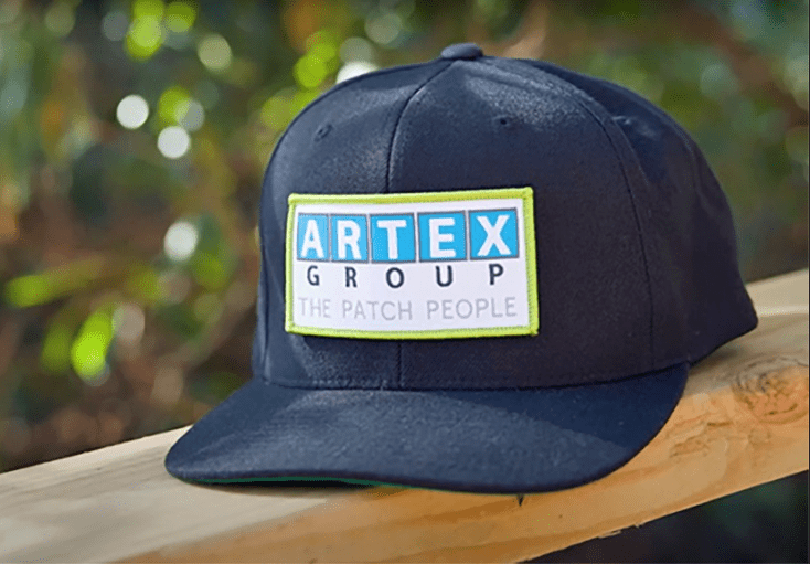 Black cap featuring Artex Group logo patch with 'The Patch People' slogan, emphasizing custom embroidered branding on headwear.