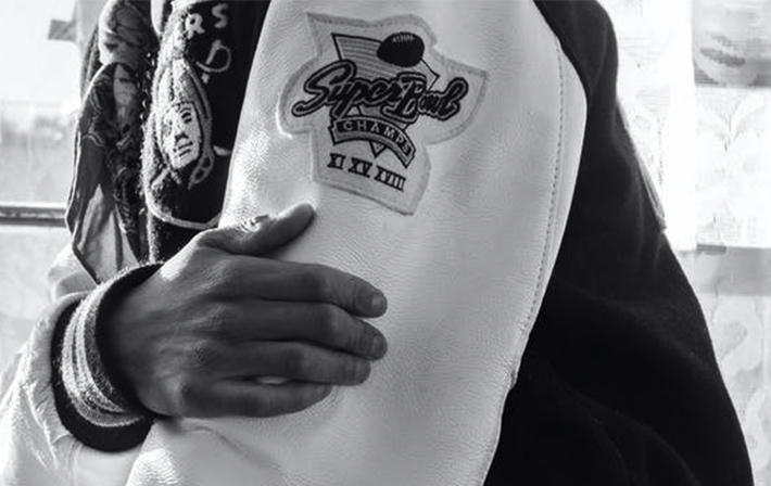 Black and white photo of a Super Bowl Champions patch on a white varsity jacket sleeve, celebrating football championship achievements.